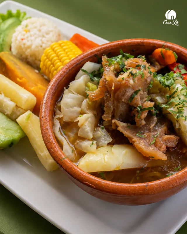 Caldo servido en cazuela de barro con elote, verduras y arroz