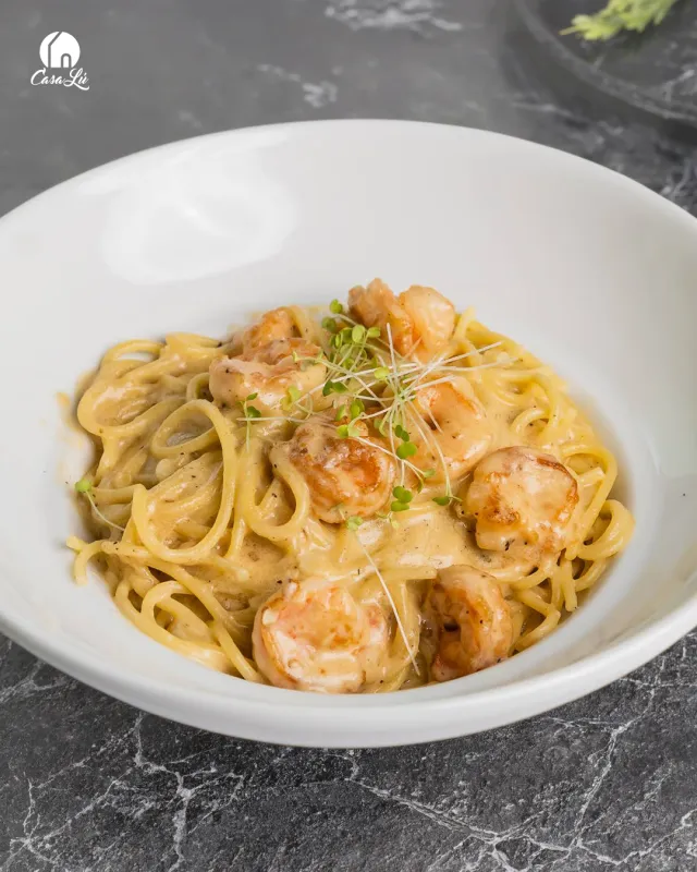 Pasta con camarones en salsa cremosa servida en plato blanco