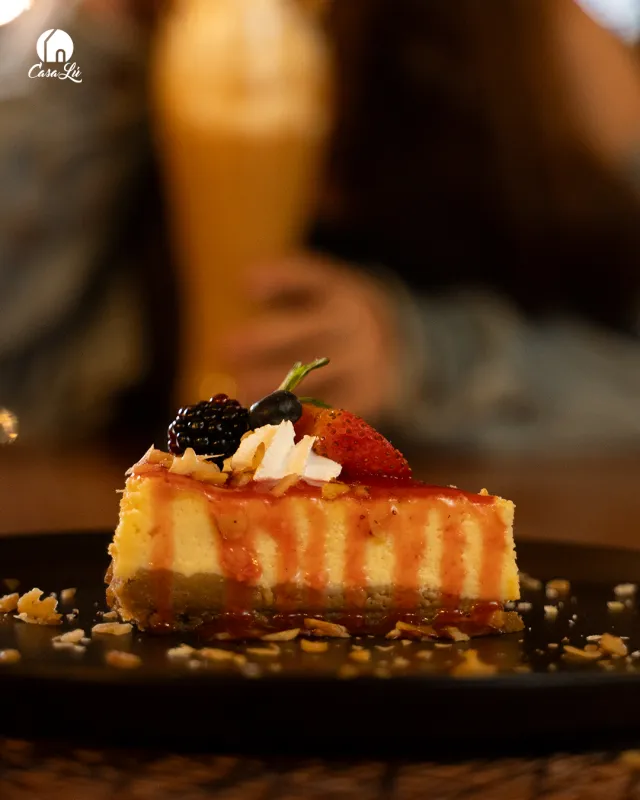 Cheesecake con frutos rojos servido sobre tabla oscura