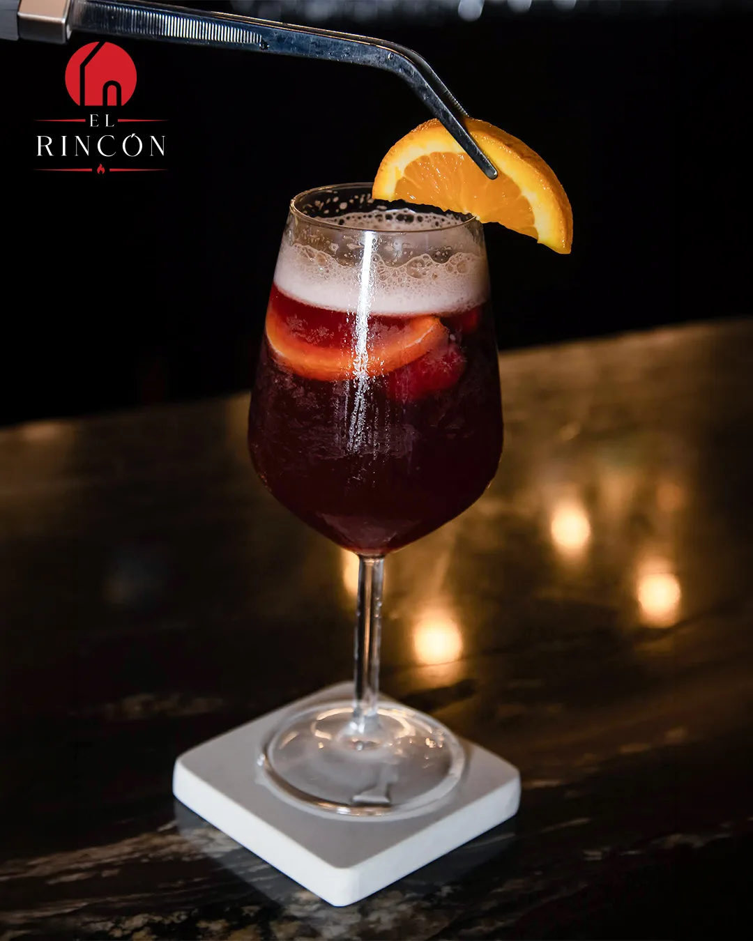 Copa de sangría con naranja en la barra de El Rincón